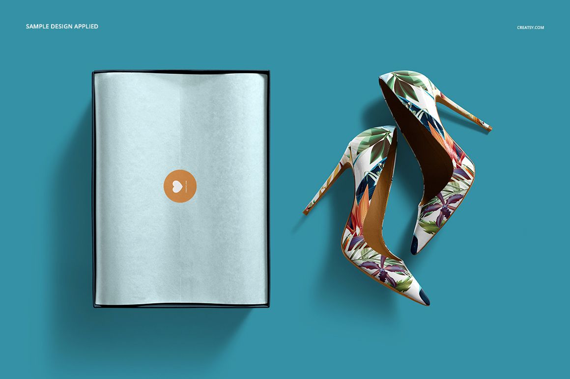 PSD mockup featuring floral print high heels and an open shoe box with tissue paper, arranged on a blue backdrop.