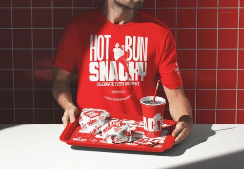 Red fast food branding mockup featuring a man, wrapped burgers, fries, and a drink cup against a tiled wall.