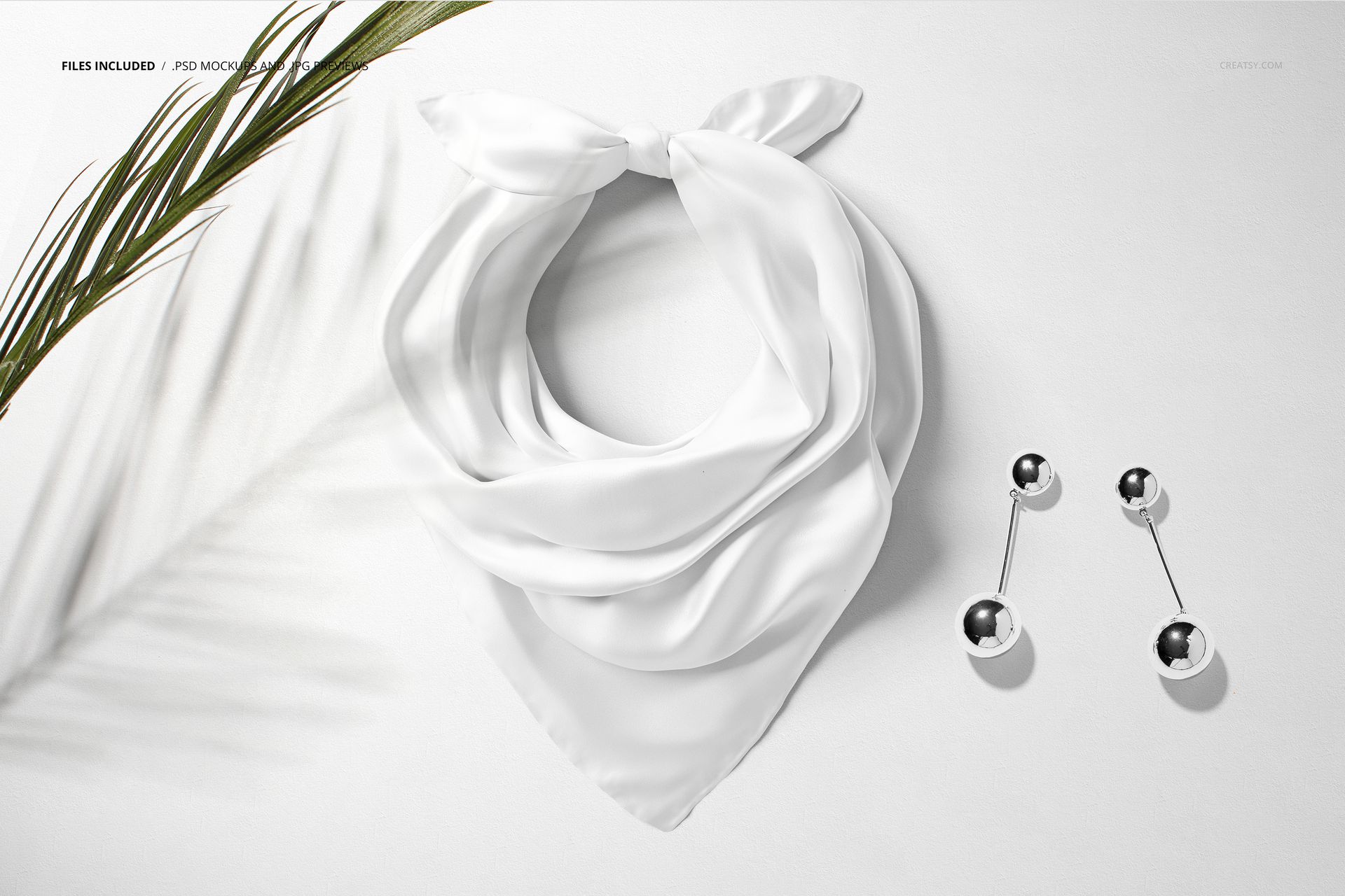 White silk scarf mockup displayed from above, featuring soft folds and silver ball earrings on a plain background.