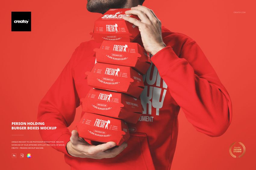 PSD mockup showing a person grasping multiple red burger boxes in a vertical pile, set against a matching red wall.