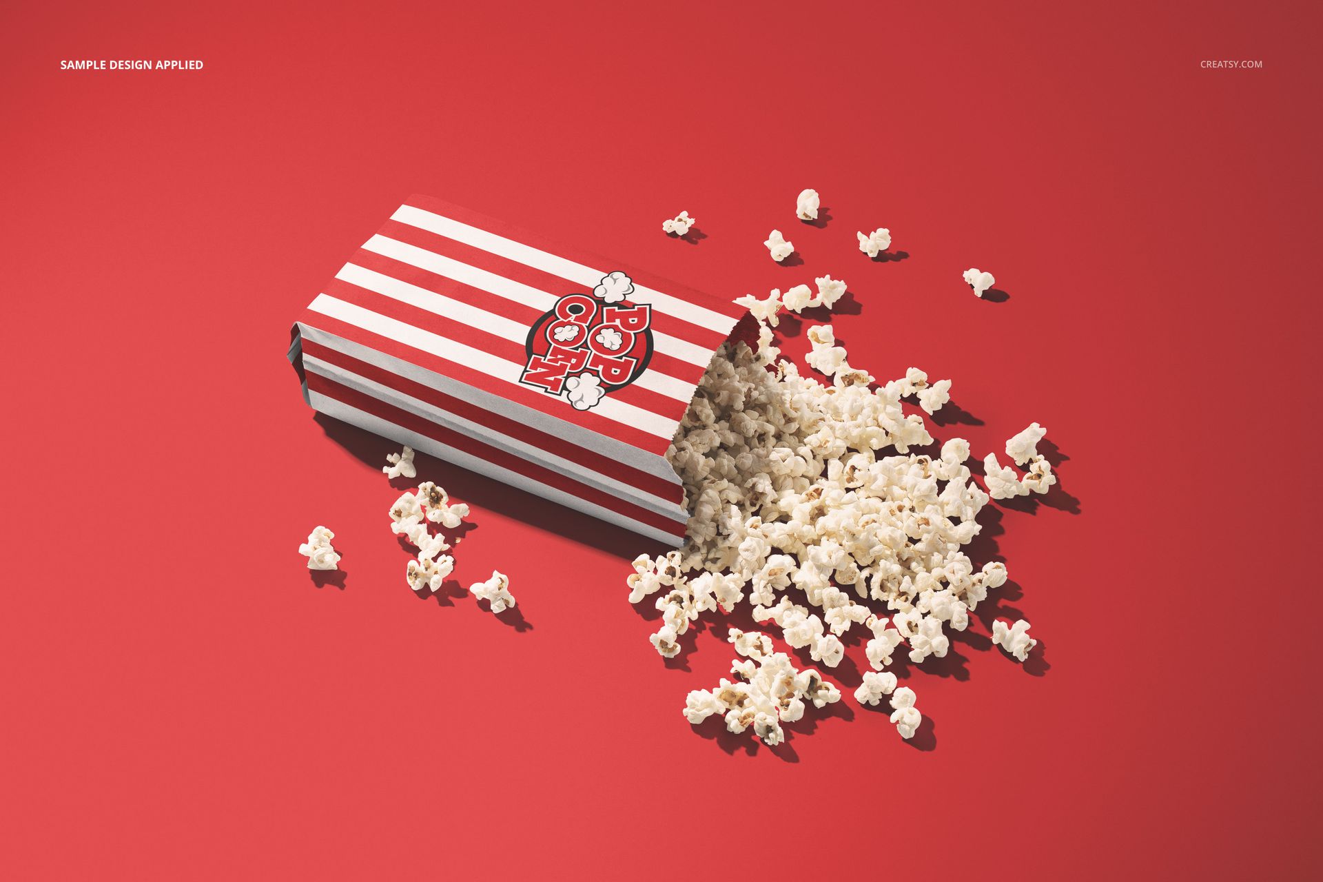 Popcorn paper bag mockup featuring a striped design, shown from an angled top view with popcorn scattered around.