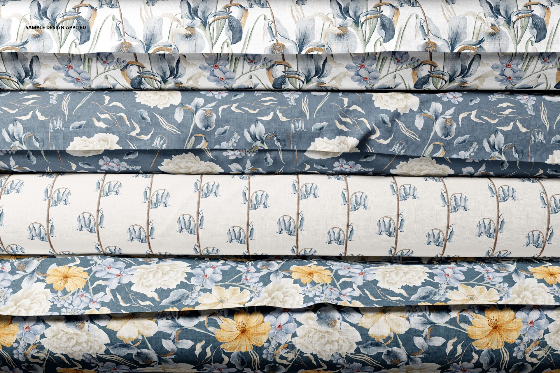 Stacked rolls of fabric with various floral patterns in blue, white, and yellow tones, viewed from the front.