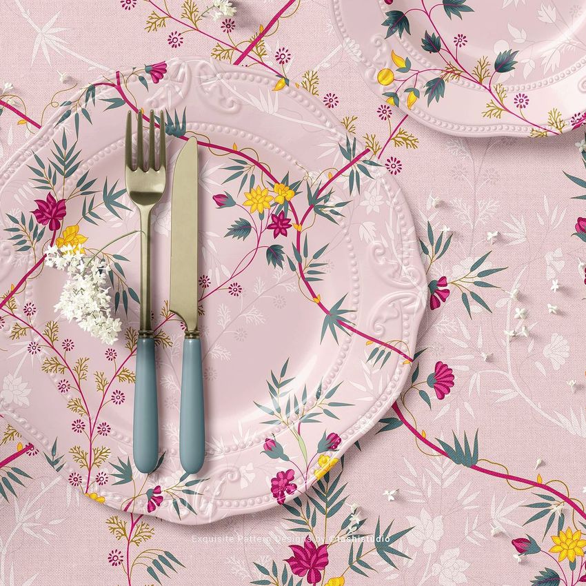 Placemat mockup showing a pink plate with floral patterns, a matching napkin, and cutlery on a decorative table setting.