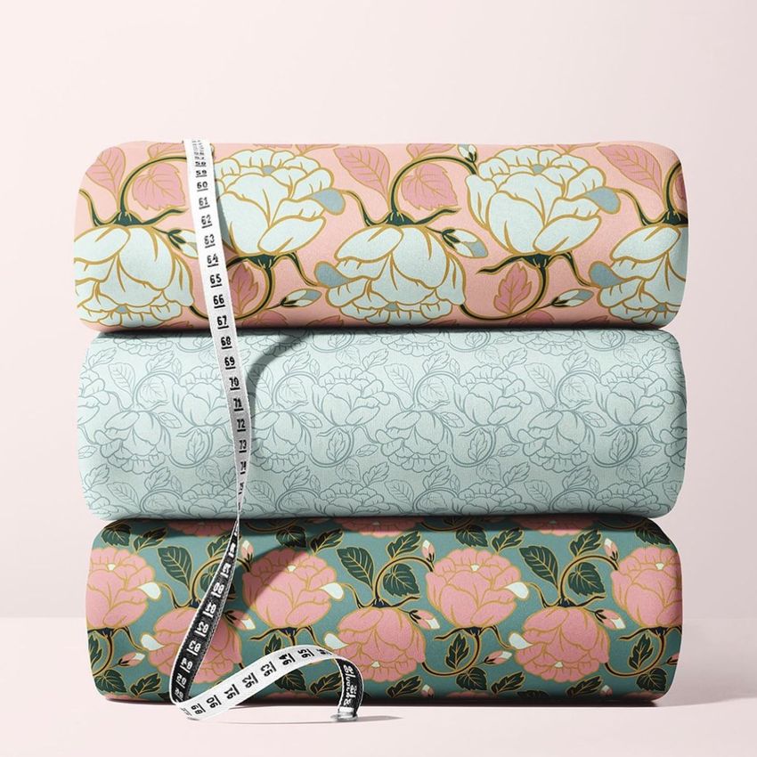 Scuba fabric mockup featuring three stacked fabric bolts with floral rose patterns in pink, light blue, and dark green tones.