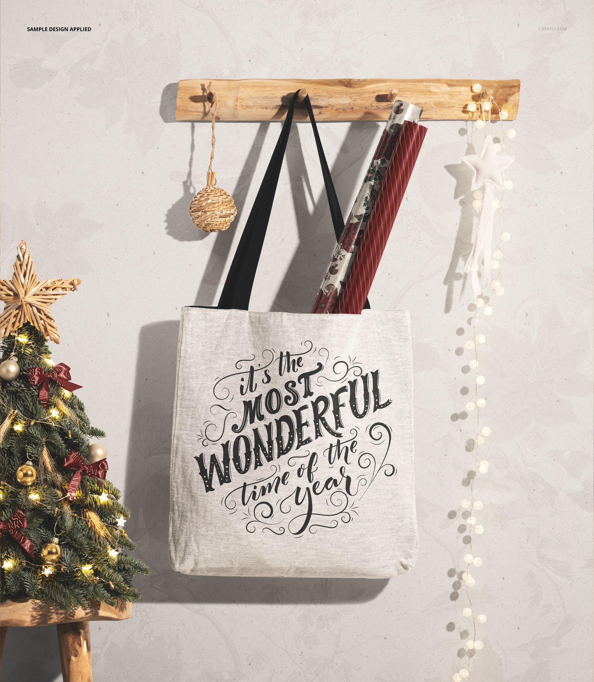 Christmas woven tote bag mockup displayed on a wall hook, with festive ornaments and rolled wrapping paper inside.