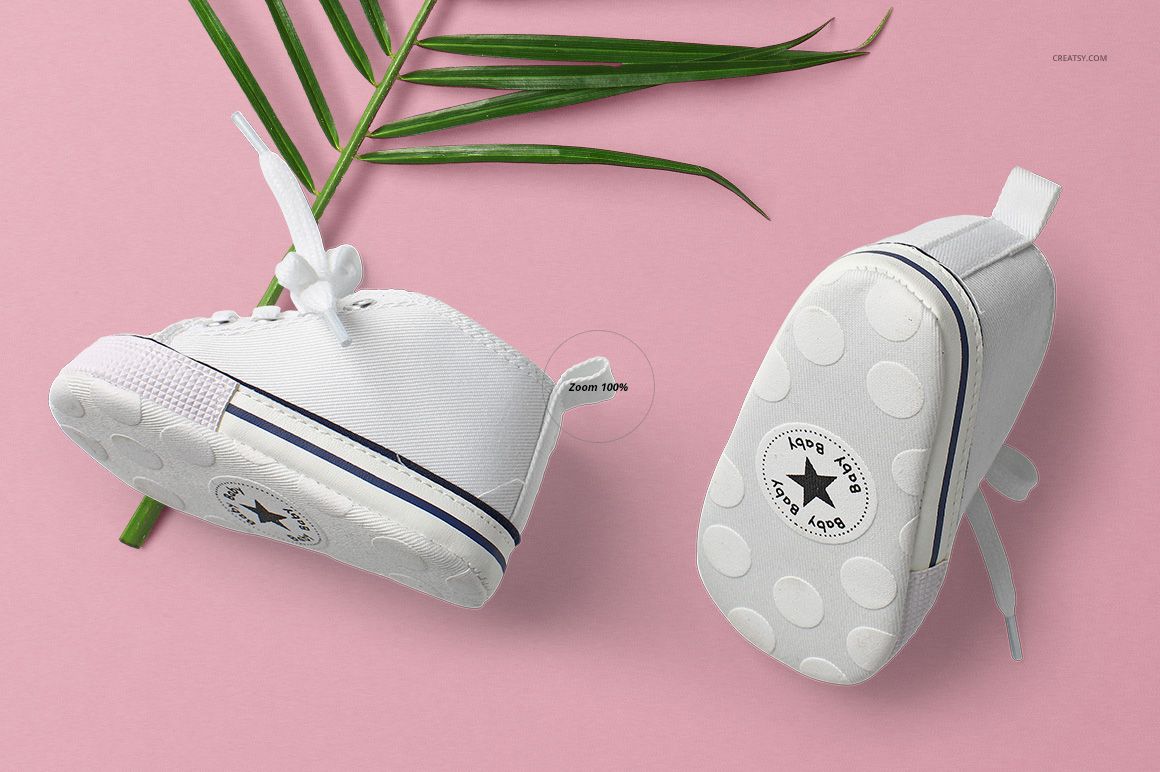 Mockup of two white baby tank tops on a pink backdrop, highlighting garment details and a touch of natural greenery.