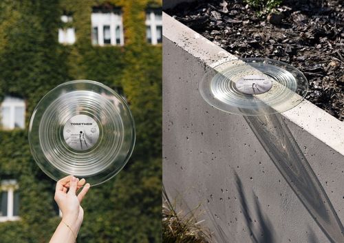 Transparent vinyl record mockup displayed outside, with one in hand near a building and one on a ledge in sunlight.