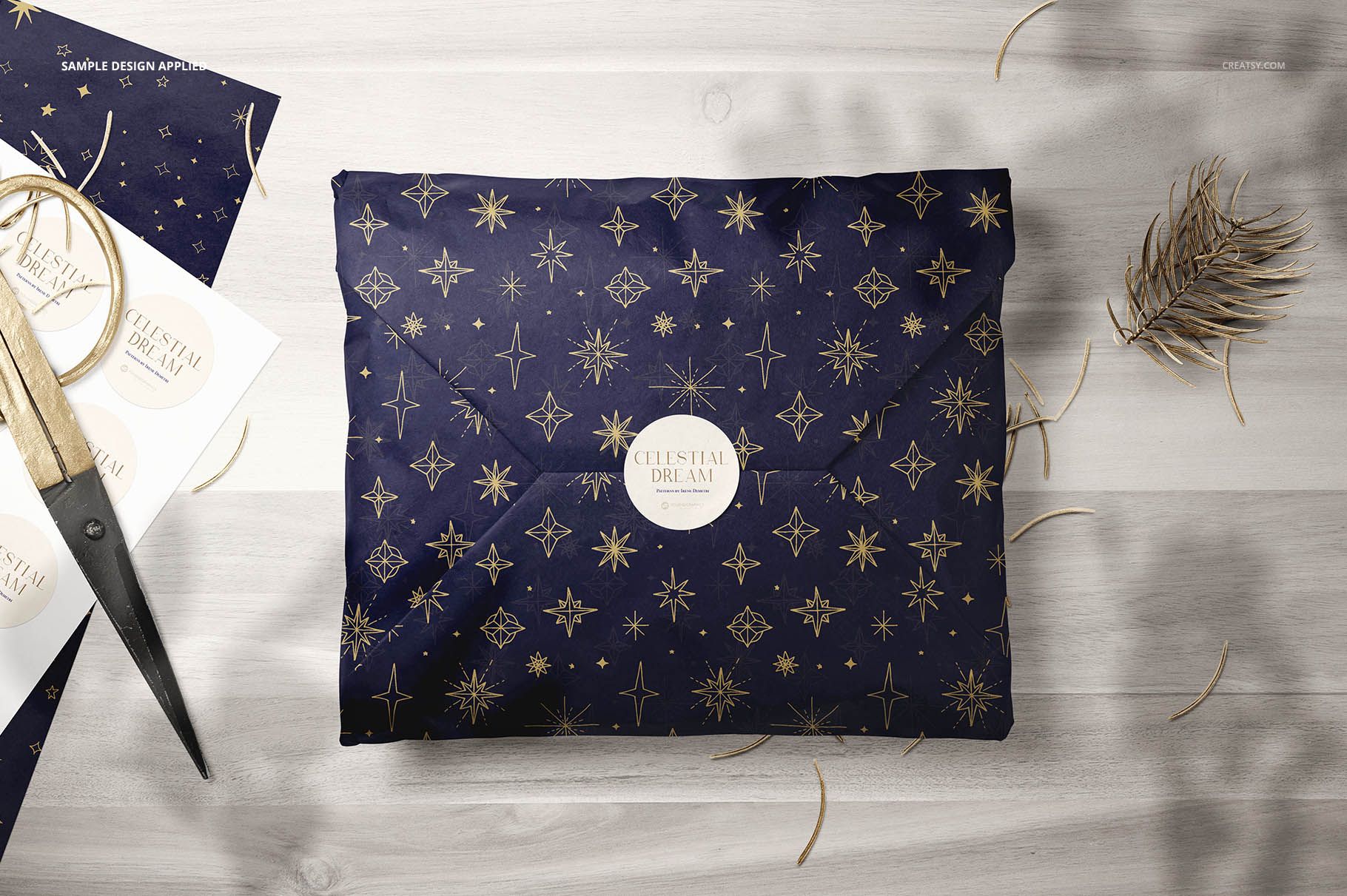Mockup of dark blue tissue paper featuring gold stars, displayed flat on a wooden table with scissors and twine nearby.