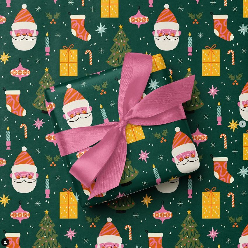 Square gift box mockup wrapped in green paper with Santa faces, pink ribbon, and Christmas-themed pattern on background.