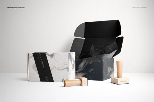 Mockup of two packaging boxes with marbled designs, one closed and one open, with wooden stamps beside them.