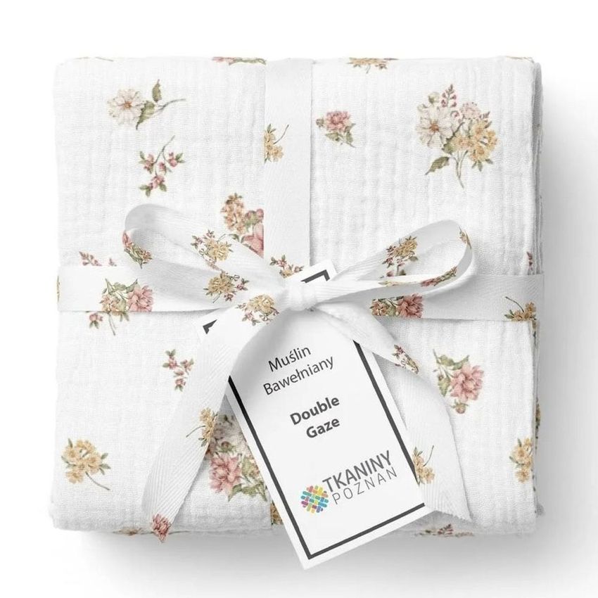 Crinkle muslin swaddle blanket mockup featuring a folded white blanket with pastel floral patterns, tied with a white ribbon and tag.