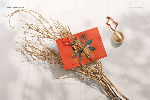 Rectangular card mockup featuring a vivid red color and leaf illustration, arranged with twigs and a gold ornament.