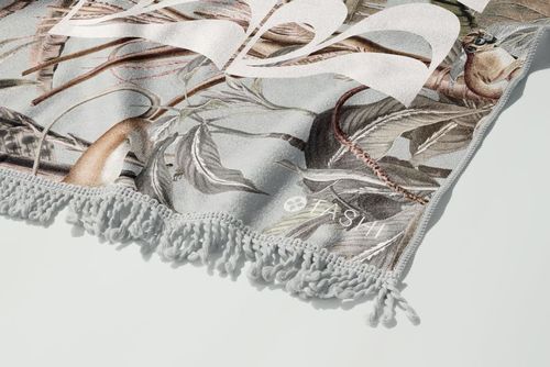 Detailed PSD mockup of a fringed beach towel featuring a nature-inspired print and soft decorative tassels.