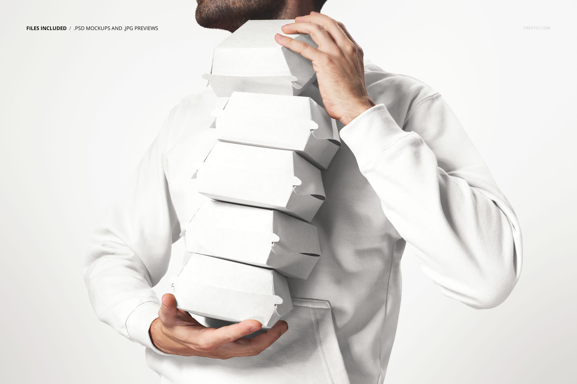 PSD mockup featuring a person holding multiple white packaging boxes, captured from the front against a light backdrop.