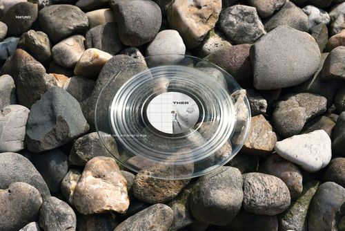 PSD mockup featuring a clear vinyl record set on textured stones, highlighting the record's shape and subtle reflections.