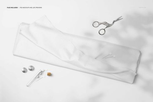 Flat lay of a white fabric bolt mockup with tulip pins and metal sewing tools arranged on a bright background.