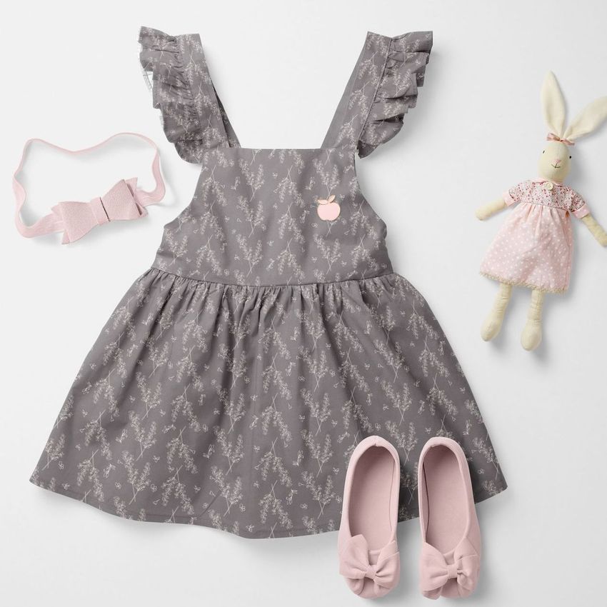 Baby dress mockup featuring a gray dress with a delicate floral pattern, ruffled straps, and pink accessories on a white background.