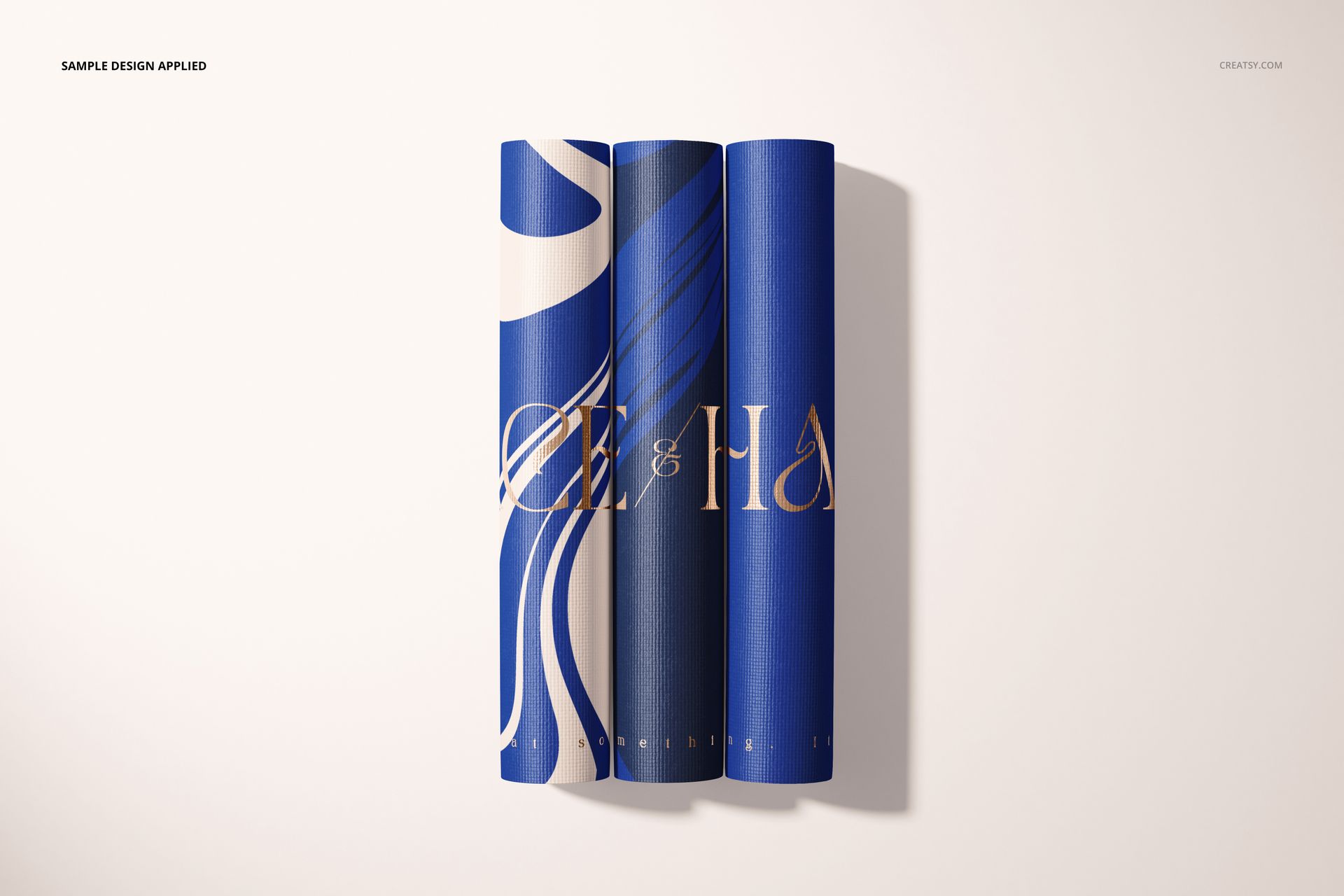 Yoga mat PSD mockup showing three mats in deep blue with wavy white and gold patterns, viewed from above.
