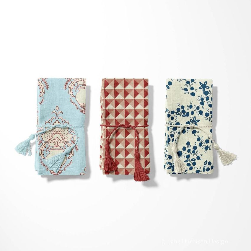 Cotton linen napkin mockup featuring three folded napkins with different patterns and tassel ties on a light background.