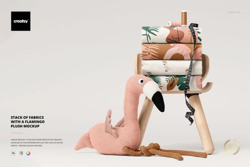 PSD mockup showing assorted patterned fabrics piled on a stool, accompanied by a pink flamingo plush, tape measure draped.