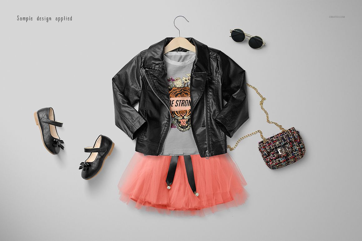 Girls chic outfit mockup featuring a black faux leather jacket, graphic t-shirt, coral tulle skirt, and accessories on a hanger.