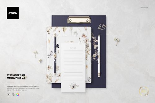 Top view of a stationery mockup set featuring a navy clipboard, floral planner, pencil, and notepad on marble background.