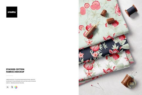 Stacked cotton fabrics in floral patterns, shown from a top angle with sewing threads and needles beside the textiles.