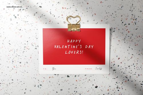 Greeting card mockup featuring a red Valentine’s message, gold heart clip, and terrazzo background in top view.
