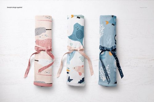 PSD mockup of three patterned baby blankets, each tied with a ribbon, arranged on a white textured tabletop.