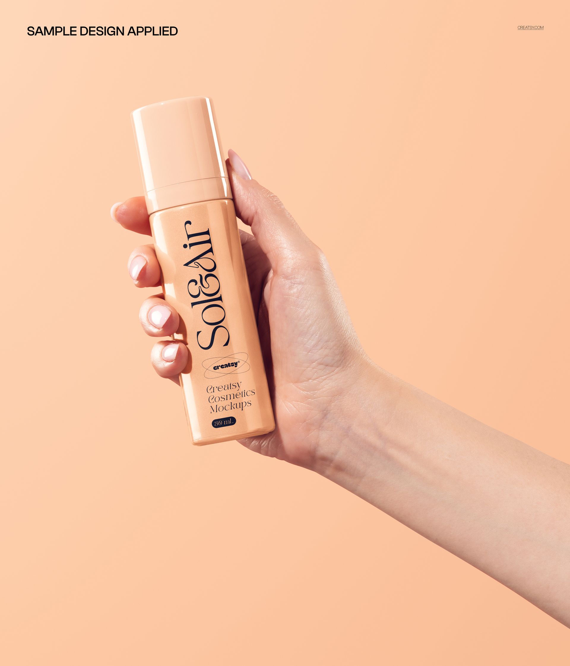 Hand holding a cylindrical cosmetic bottle with a beige label on a light peach background, front view mockup.