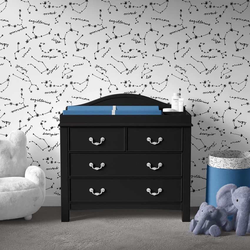 Baby room changing pad mockup showing a black dresser with a blue changing pad, set against a constellation-patterned wallpaper.