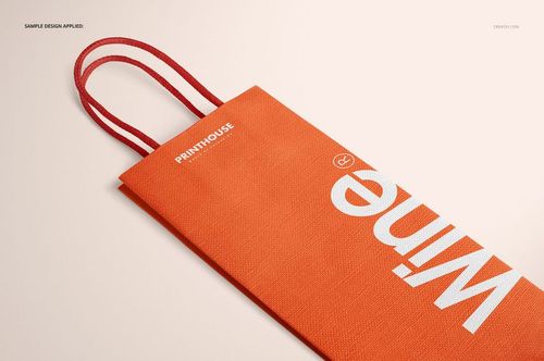 Eurotote wine tote bag mockup featuring textured orange material, red handles, and bold white lettering from a side angle.