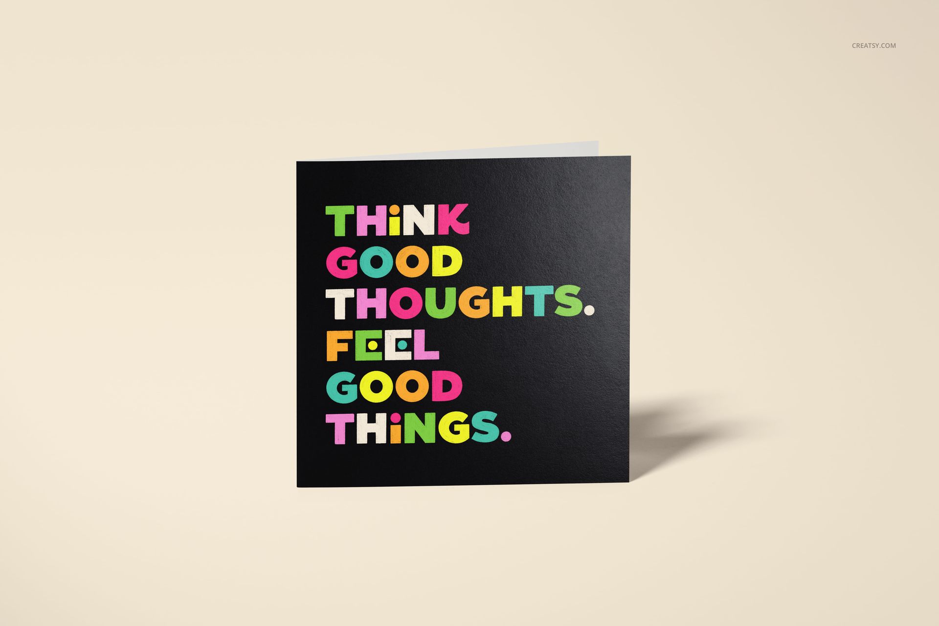 Square greeting card mockup featuring bold, colorful text on a black cover, shown from a front view on a neutral background.