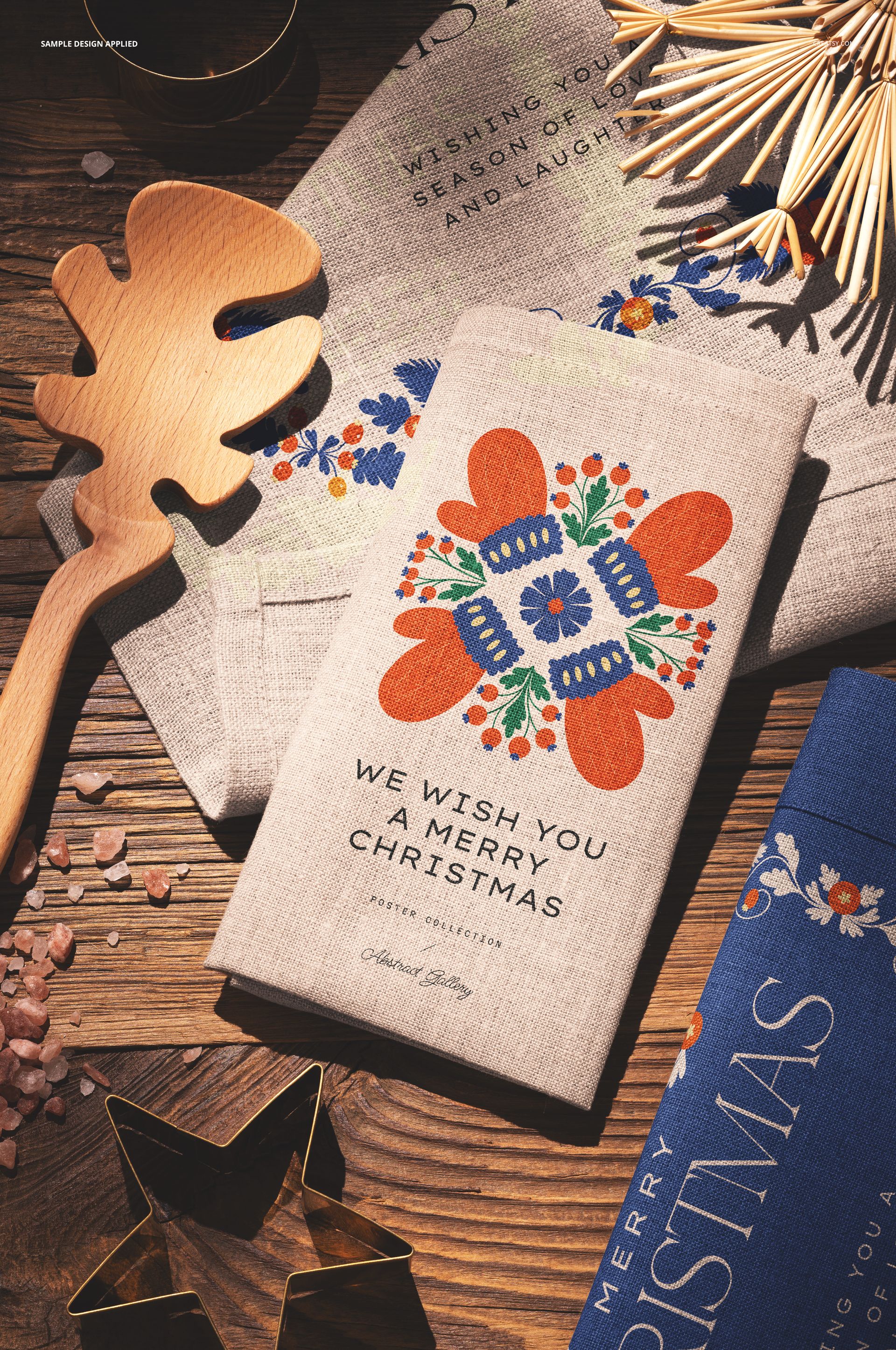 Festive linen kitchen towels mockup featuring Christmas motifs and greetings, arranged with decorative utensils and ornaments.