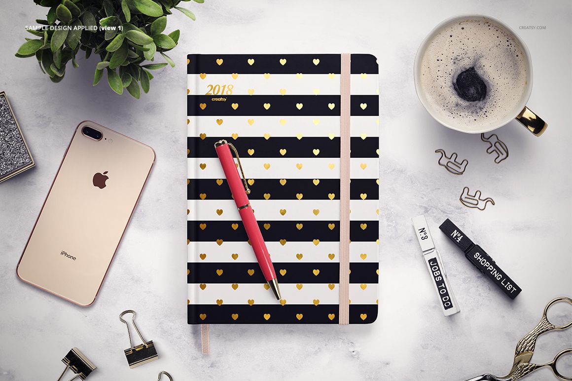 Top view of a planner mockup with black and white stripes, gold hearts, and a pen, surrounded by office items.