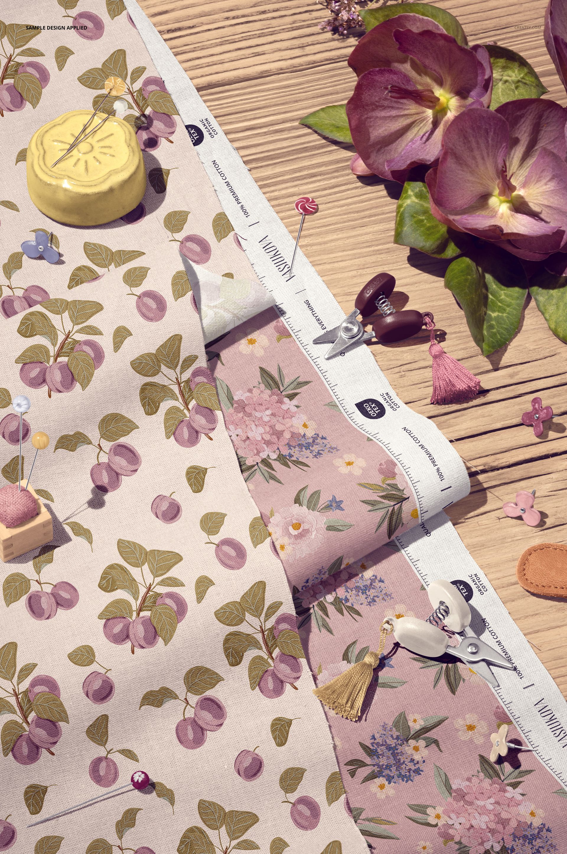Cotton fabric mockup with floral and cherry patterns displayed on a wooden surface, surrounded by sewing tools.