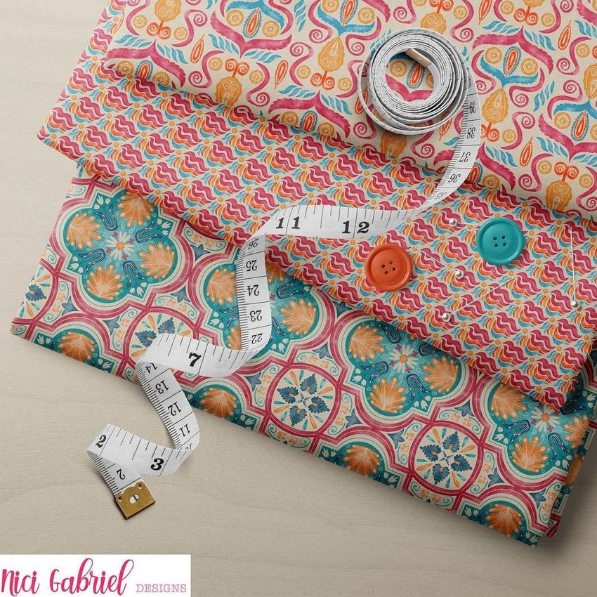 Folded fabrics mockup featuring three patterned fabric pieces with colorful designs, measuring tape, and buttons on a neutral surface.