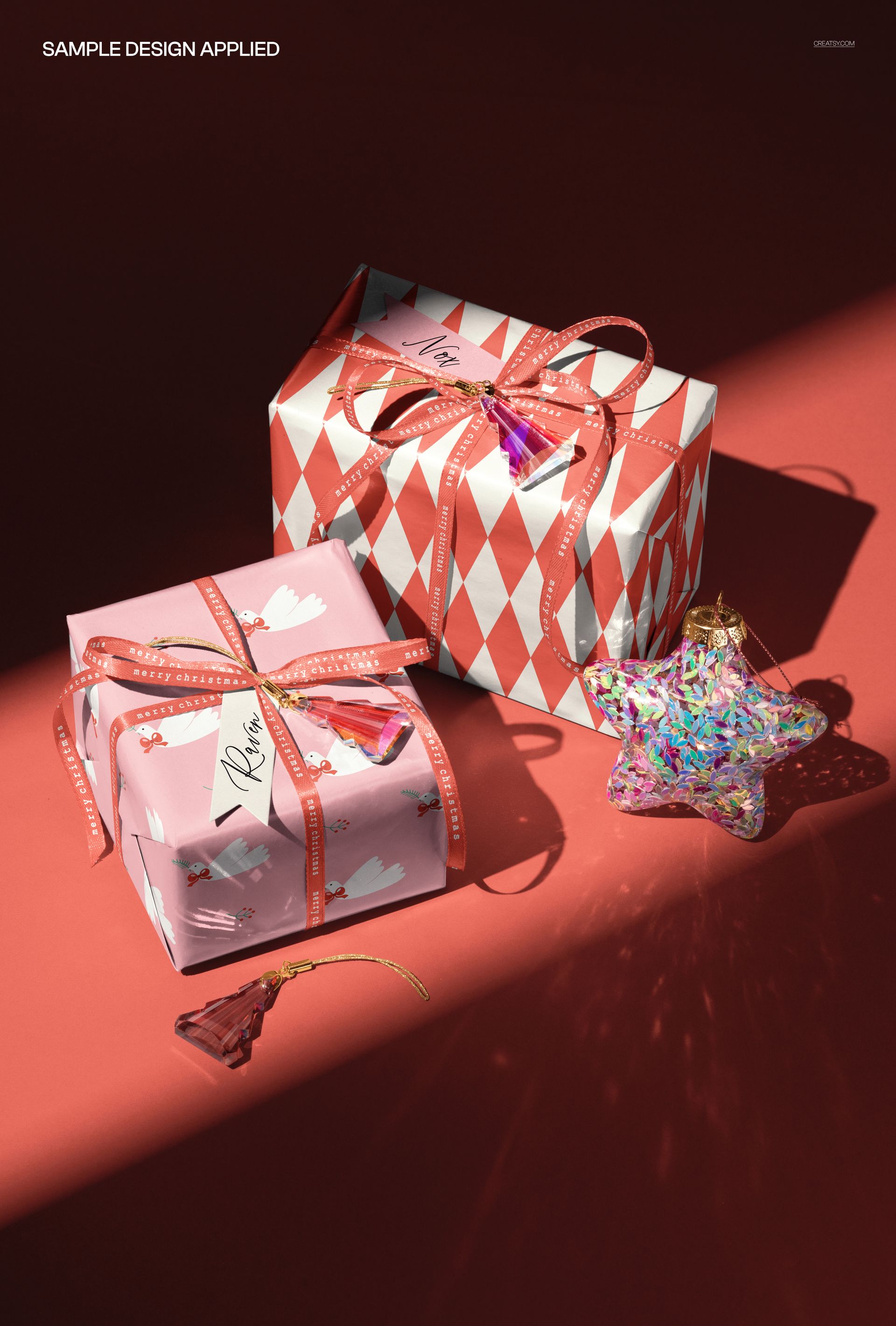 PSD mockup showing two wrapped Christmas presents with bows and star-shaped ornaments on a red tabletop, overhead perspective.