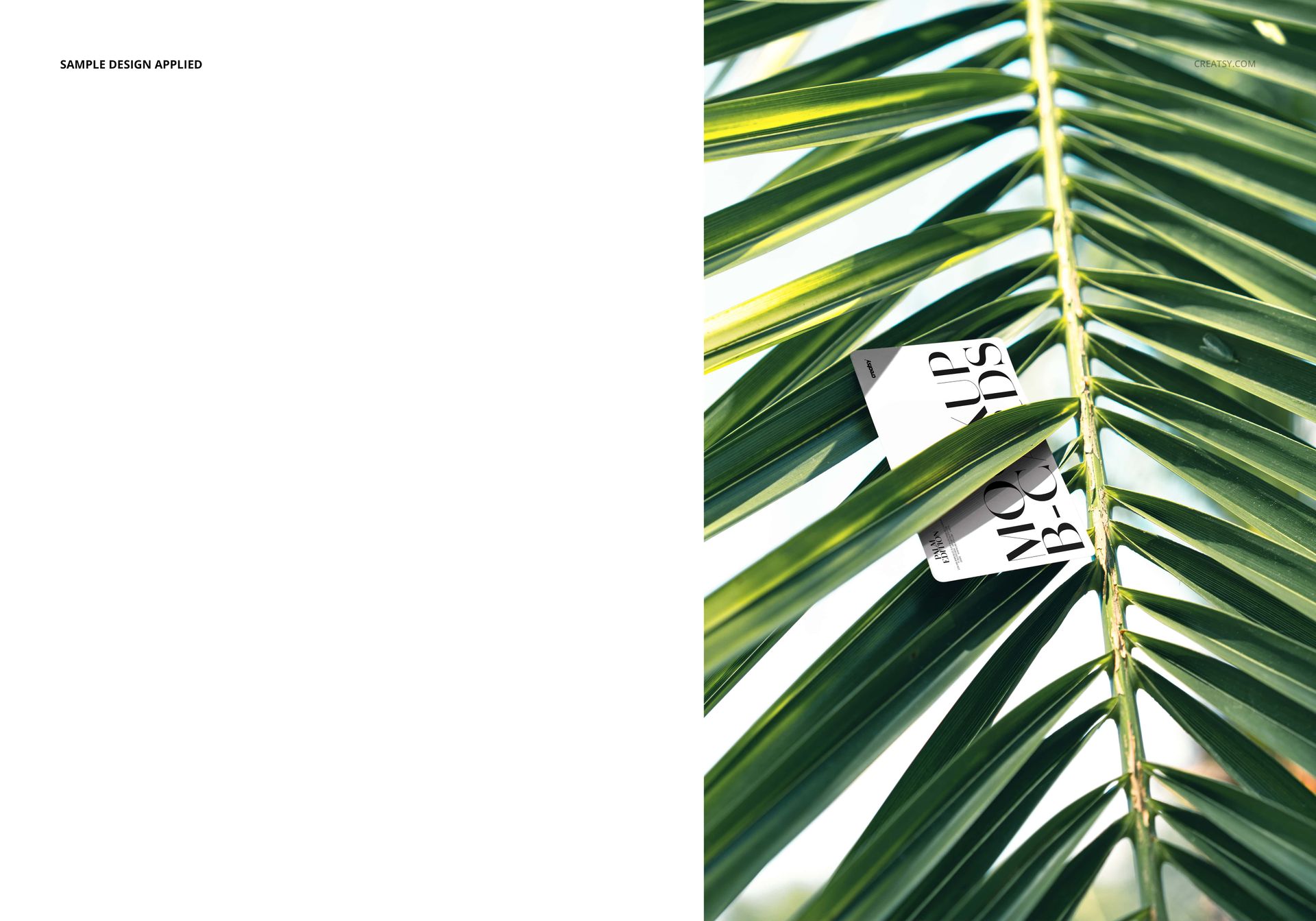 Rectangular business card mockup nestled among vibrant green palm leaf fronds, shown in a top-down perspective.