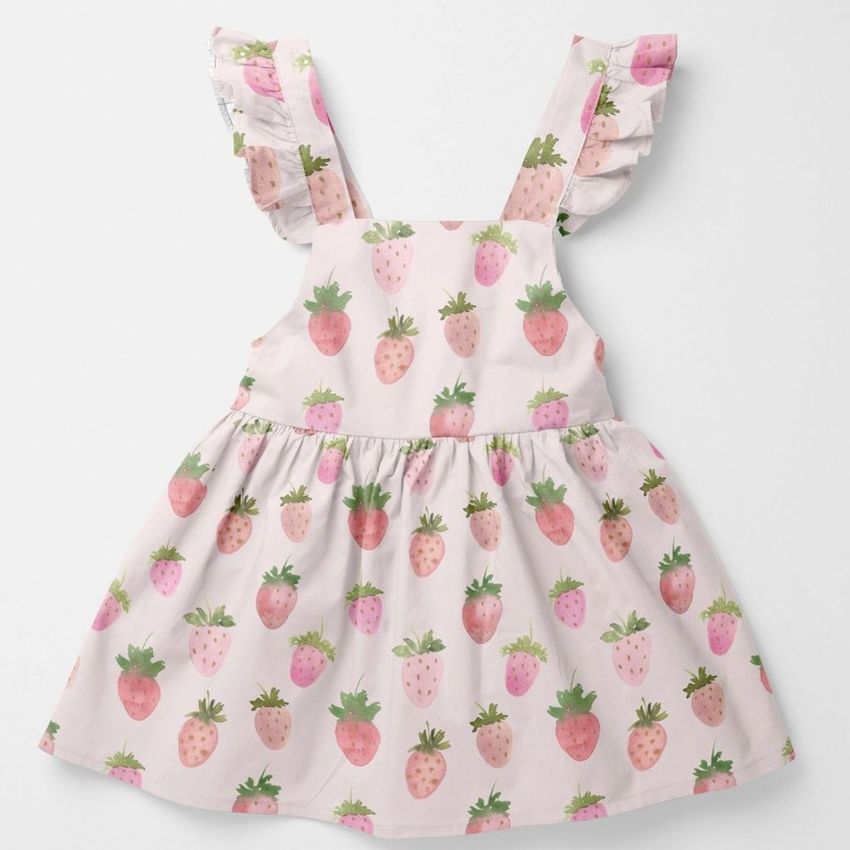 Baby dress mockup featuring a light pink fabric with a watercolor strawberry pattern, shown flat on a white background.