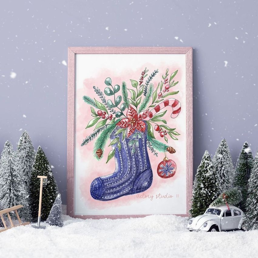 Christmas picture frame mockup featuring a festive illustration of a stocking with greenery and ornaments, set in snowy scenery.