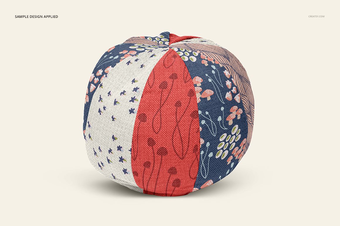 Round pillow mockup displaying alternating fabric panels in navy, red, and off-white with whimsical nature motifs.