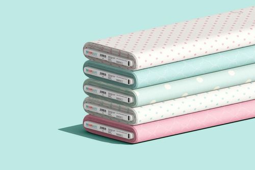 PSD mockup featuring a side view of fabric bolts in pink, mint, and white shades with subtle printed patterns.