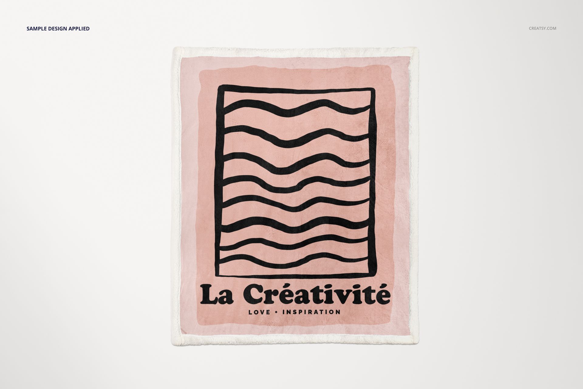 Top view of a sherpa blanket mockup featuring a pink field, abstract black waves, and bold French lettering.