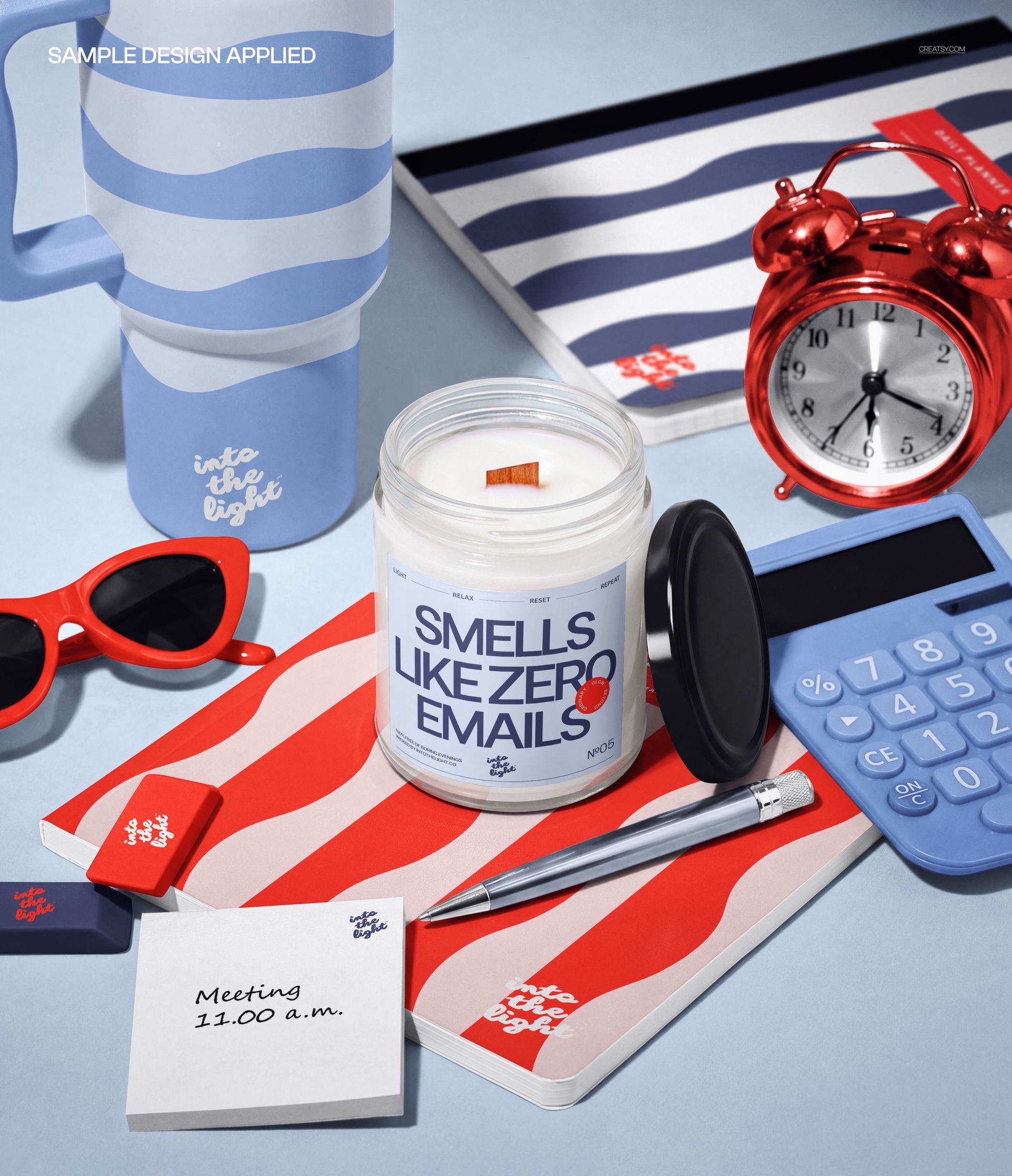 Desk scene featuring a white scented candle mockup, blue calculator, red sunglasses, striped stationery, and pen.