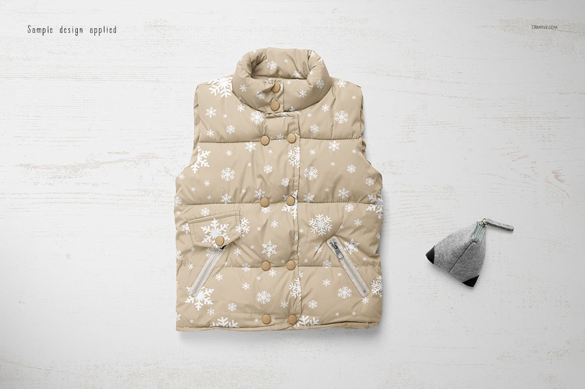 Boys winter set mockup featuring a beige padded vest with snowflake design and a gray hat, shown from above on a wooden background.