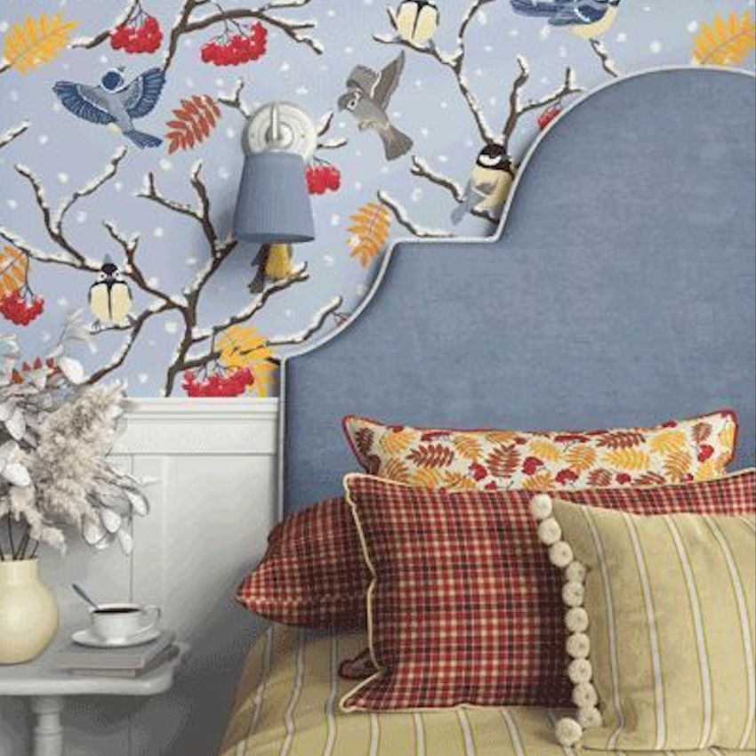 Bedroom mockup with a blue upholstered headboard, patterned pillows, and wallpaper featuring birds on snowy branches.