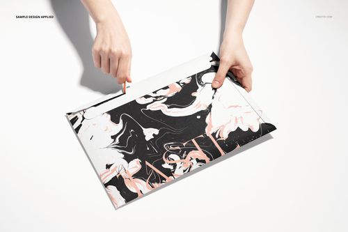 Top view of a tear strip envelope mockup featuring swirling black, white, and peach colors, held by two hands.