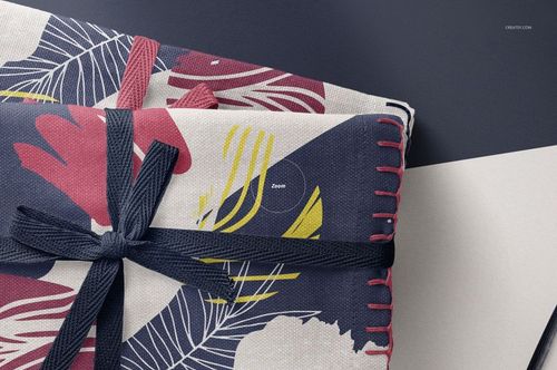 Close-up of folded linen fabric mockup featuring navy, pink, and yellow leaf designs and a dark ribbon accent.