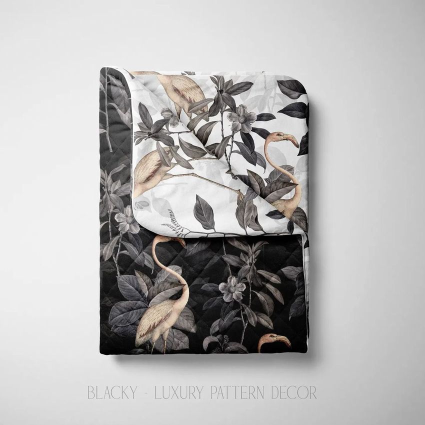 Double-sided baby bedding set mockup showing folded bedding with a botanical and flamingo pattern on black and white backgrounds.
